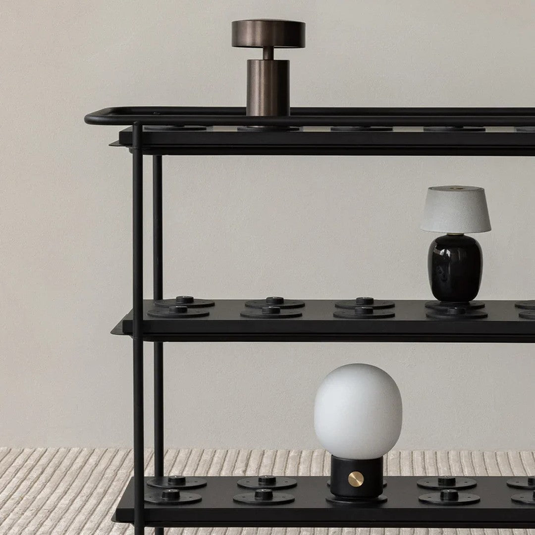 Black metal shelf featuring a mix of glossy black, matte white, and metallic accents against a neutral backdrop.