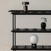 Black metal shelf featuring a mix of glossy black, matte white, and metallic accents against a neutral backdrop.