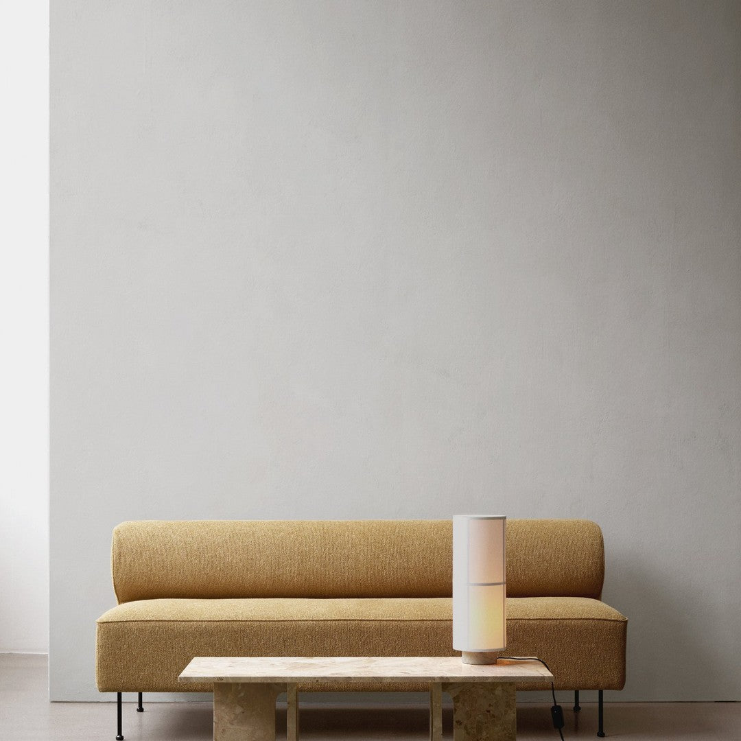Luxe mustard yellow sofa with minimalistic design, complemented by a sleek white lamp and natural stone coffee table.