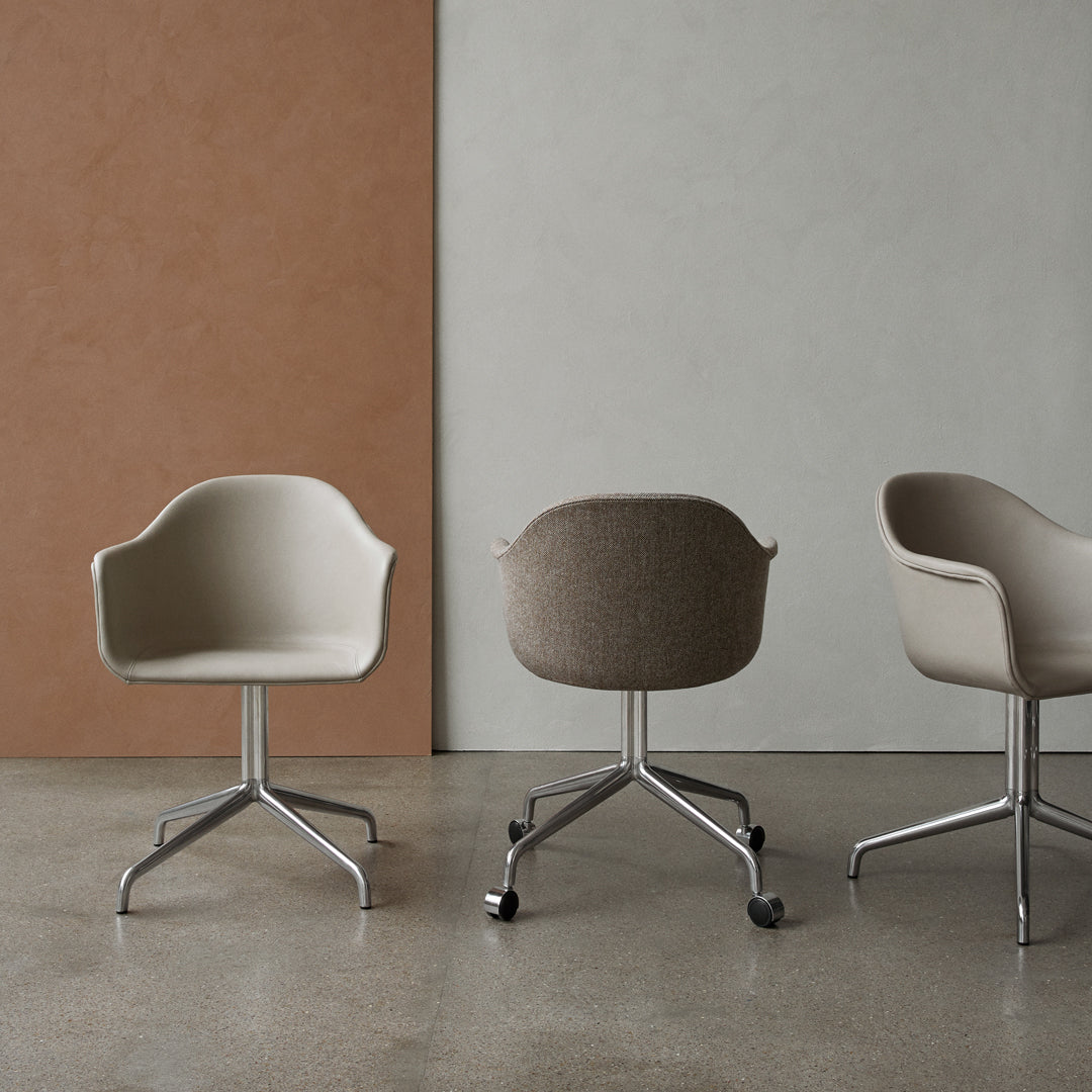 Neutral beige and soft brown armchairs with sleek silver bases against muted gray and terracotta walls.