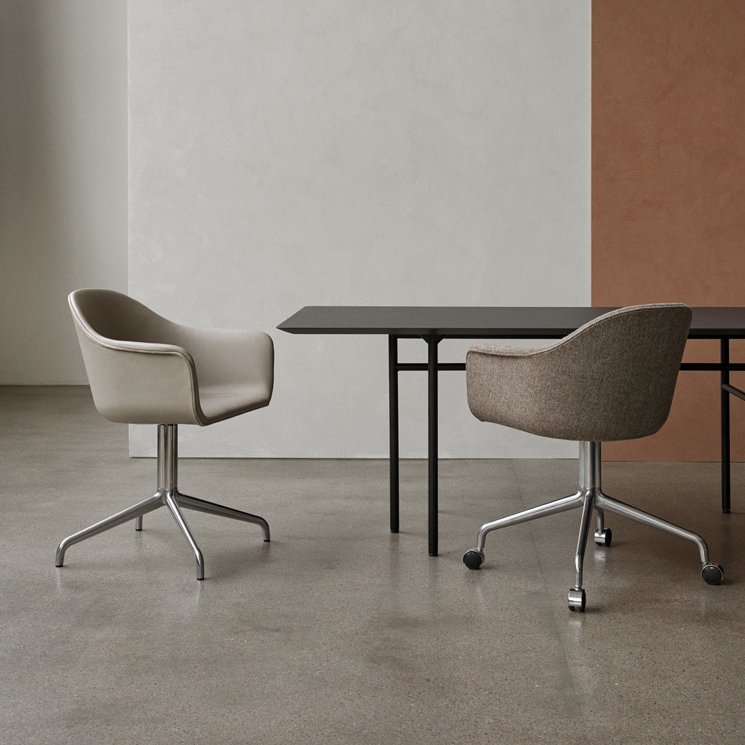 Soft beige and muted gray armchairs paired with a sleek black table against a textured white and terracotta backdrop.