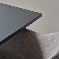 Gray table edge with a smooth matte finish beside textured beige and brown fabric, showcasing elegant color contrast.