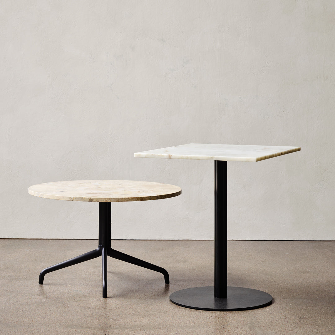 Round and square tables with white marble tops and sleek black metal bases, showcasing a chic contrast in shapes and colors.