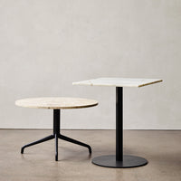 Round and square tables with white marble tops and sleek black metal bases, showcasing a chic contrast in shapes and colors.