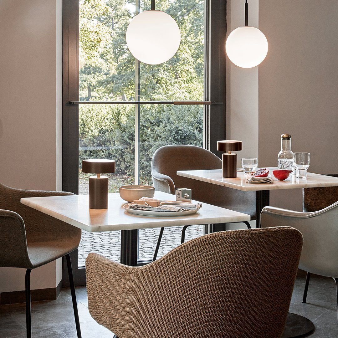 Elegant dining space featuring soft beige chairs, warm wood accents, and modern round pendant lights in a tranquil setting.
