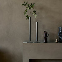Sleek black vases on a textured beige backdrop, featuring minimalist design and natural greenery accents.