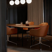 Modern dining table with warm brown leather chairs, sleek black legs, and soft beige curtains against a dark backdrop.
