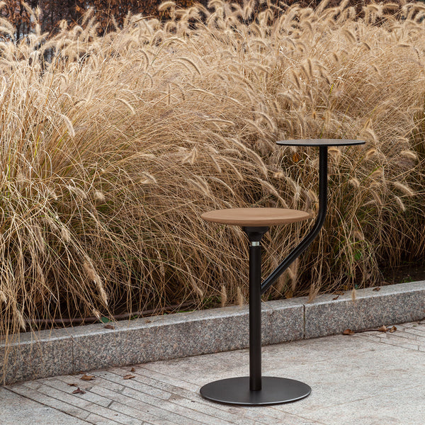Stylish black and wood bar stool with a modern design, set against a backdrop of tall golden grasses.