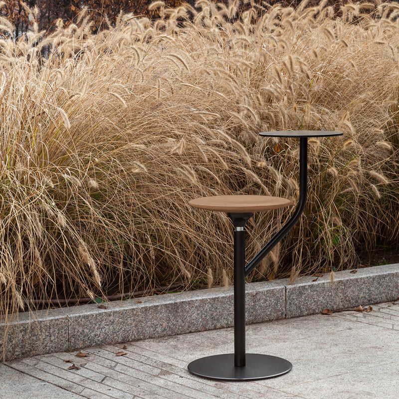 Stylish black and wood bar stool with a modern design, set against a backdrop of tall golden grasses.