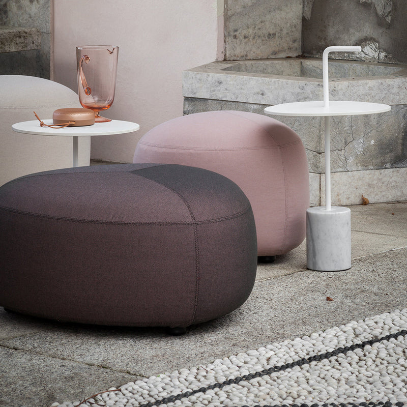 Soft pink and dark gray ottomans with a subtle two-tone pattern, paired with minimalist white and marble side tables.