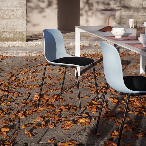 Light blue and black modern chairs on a patio with autumn leaves, showcasing a sleek and stylish outdoor vibe.