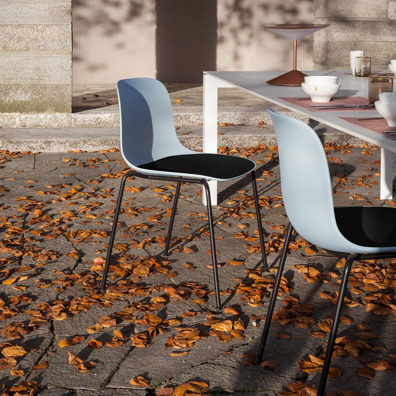 Light blue and black modern chairs on a patio with autumn leaves, showcasing a sleek and stylish outdoor vibe.