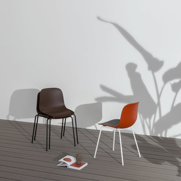 Brown and rust-colored chairs with sleek, minimalist designs, cast shadows on a light background.