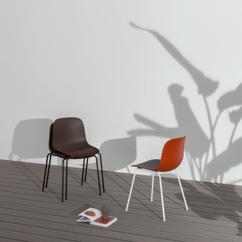 Brown and rust-colored chairs with sleek, minimalist designs, cast shadows on a light background.