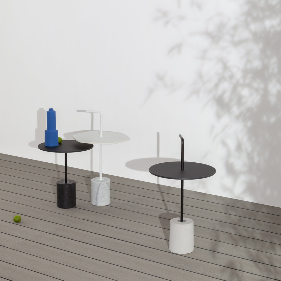 Three modern side tables in black, white, and marble with smooth circular tops and minimalist designs.