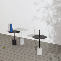 Three modern side tables in black, white, and marble with smooth circular tops and minimalist designs.