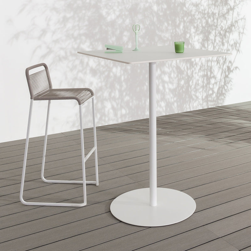 White accent table with sleek design, paired with a light gray barstool and a neutral wooden deck. Minimalistic style.