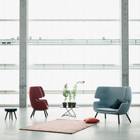 Modern living room featuring a blue armchair, red accent chair, pink rug, and a black-wire coffee table.