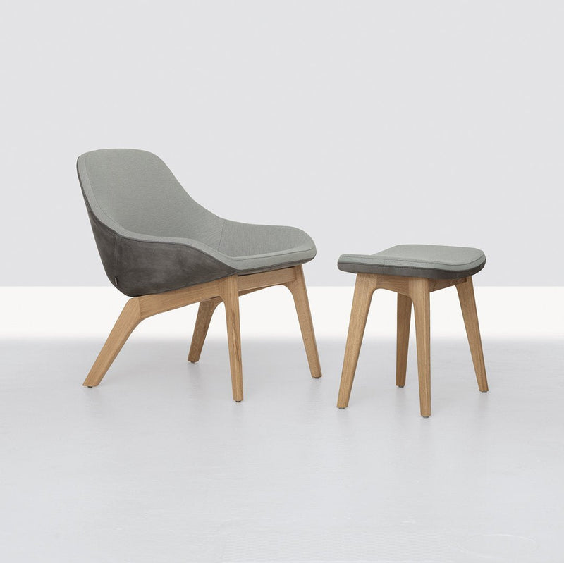 Gray upholstered chair with a matching stool, featuring smooth curves and light wood legs. Minimalist design.