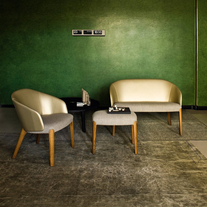 Sleek, gold and gray upholstered chairs with wooden legs against a textured green wall and light gray rug.
