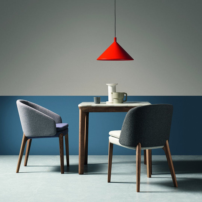 Modern dining set featuring gray and purple chairs, a wooden table, and a vibrant red pendant light against a neutral backdrop.
