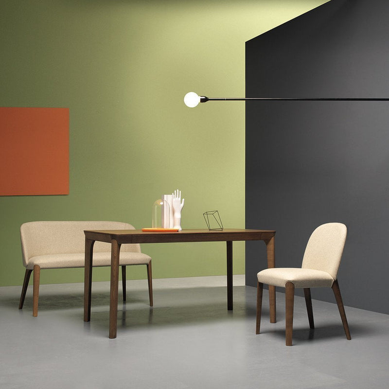 Modern dining set featuring cream upholstery, dark wood, and contemporary geometric patterns against vibrant green and gray walls.