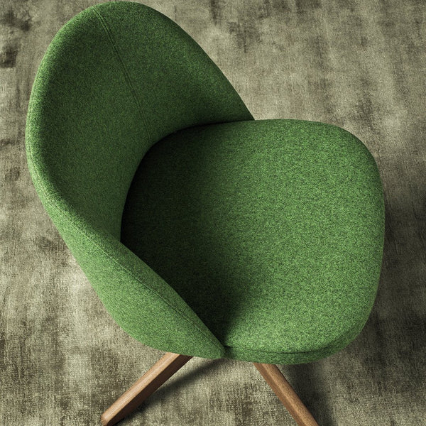 Vibrant green upholstered chair with a modern, smooth design and natural wooden legs against a textured background.