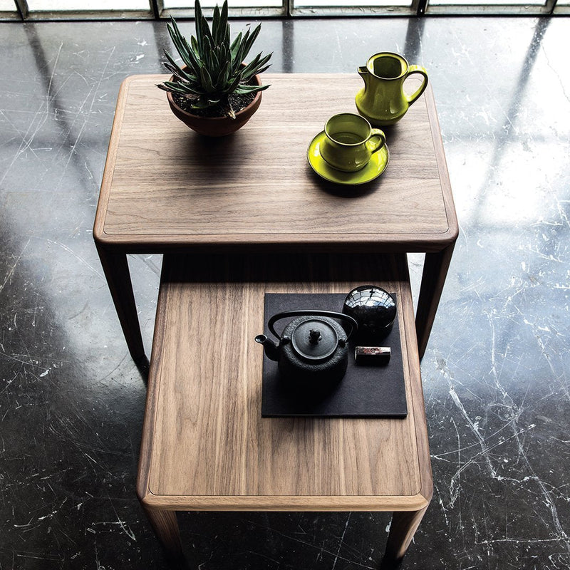 Wooden coffee tables with a natural finish, featuring vibrant green accents and a contrasting dark placemat.