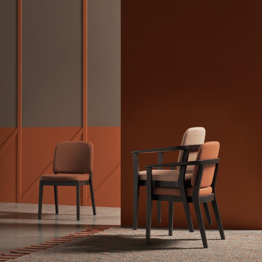 "Two modern chairs in warm brown and beige tones, set against a rich terracotta and neutral backdrop."