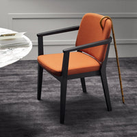 Stylish orange upholstered chair with a sleek black frame, set against a subtle gray patterned rug.