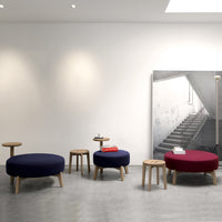 Round ottomans in navy blue and burgundy with natural wood legs, set against a minimalist backdrop.