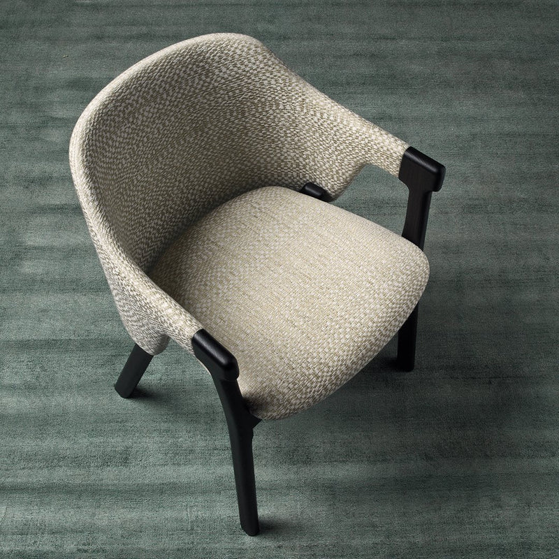 Stylish beige textured fabric chair with dark wood legs, set against a muted green background.