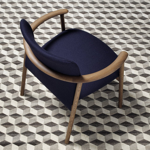 Navy blue chair with wooden arms on a geometric black and white patterned rug.