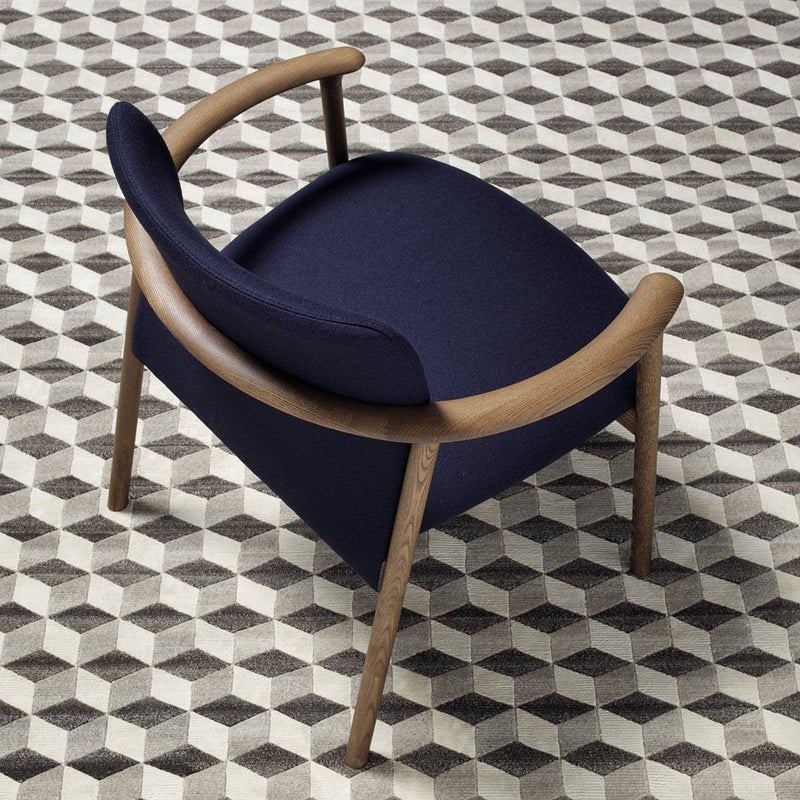 Navy blue chair with wooden arms on a geometric black and white patterned rug.