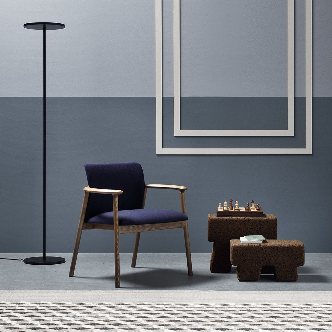 Modern blue and gray decor featuring a navy chair, earthy brown tables, and geometric patterned rug.