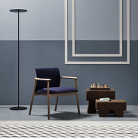 Modern blue and gray decor featuring a navy chair, earthy brown tables, and geometric patterned rug.
