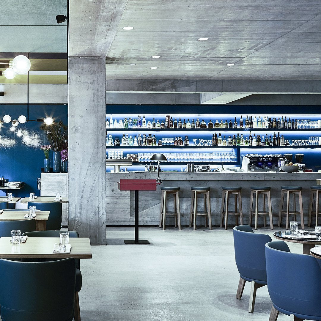 Modern restaurant interior featuring blue and gray tones, sleek concrete, and stylish furniture with circular patterns.