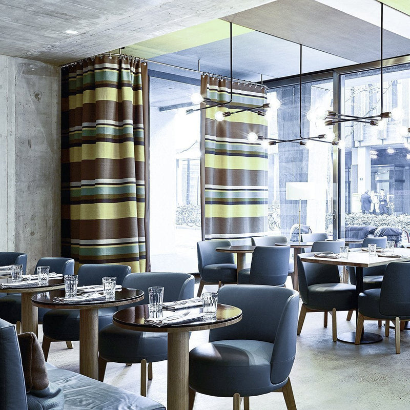 Striped curtains in brown, yellow, and green complement blue chairs in a modern dining space.