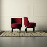 Plush burgundy chairs with smooth upholstery, showcasing a modern design against a textured, neutral rug.