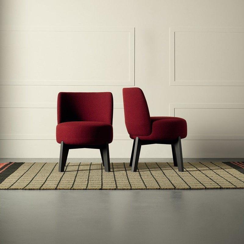 Plush burgundy chairs with smooth upholstery, showcasing a modern design against a textured, neutral rug.