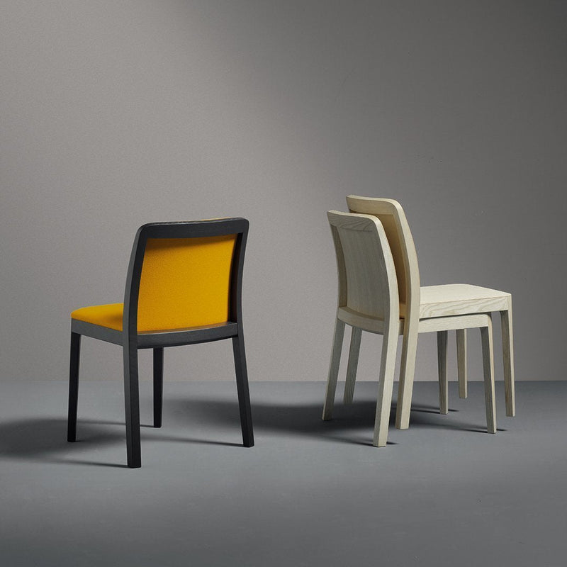 Three modern dining chairs: one with a striking yellow seat and gray frame, and two in soft white tones.