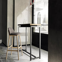 Sleek black metal frame with light wood top, complemented by textured gray upholstered barstool in a modern setting.