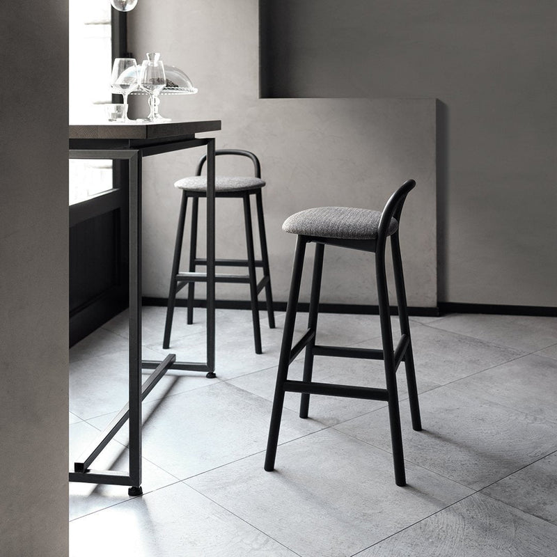 Minimalist black bar stools with gray upholstered seats, set against a sleek gray tiled floor. Modern and stylish design.