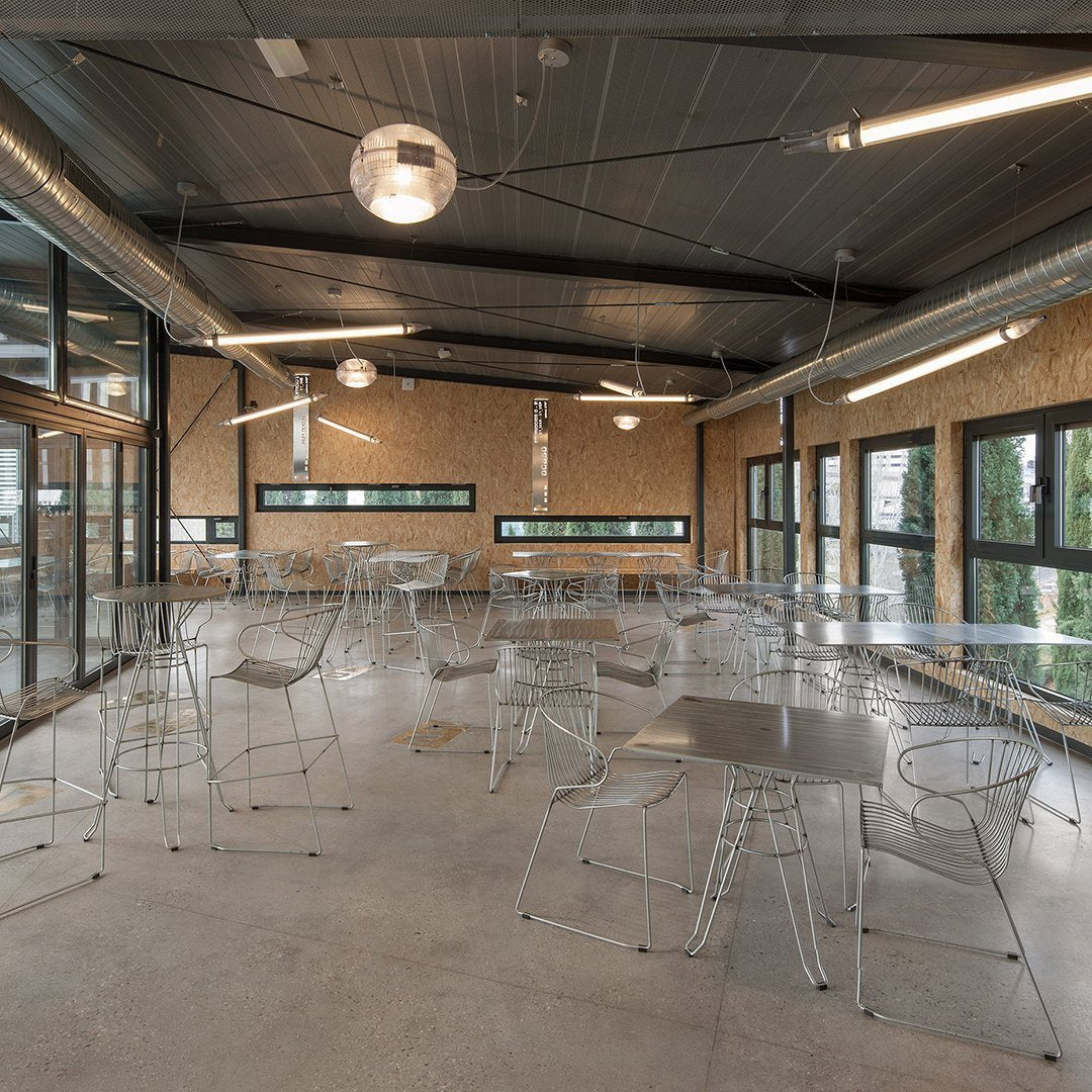 Stylish clear acrylic chairs and tables in a modern, open-space setting with neutral tones and industrial accents.