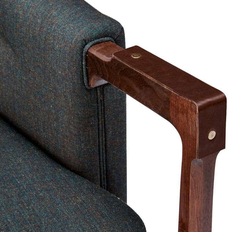 "Close-up of a teal and brown armchair with textured fabric and wooden armrest detailing."