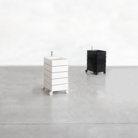 White and black storage carts with a sleek, minimalist design and smooth, matte finishes on a polished concrete floor.