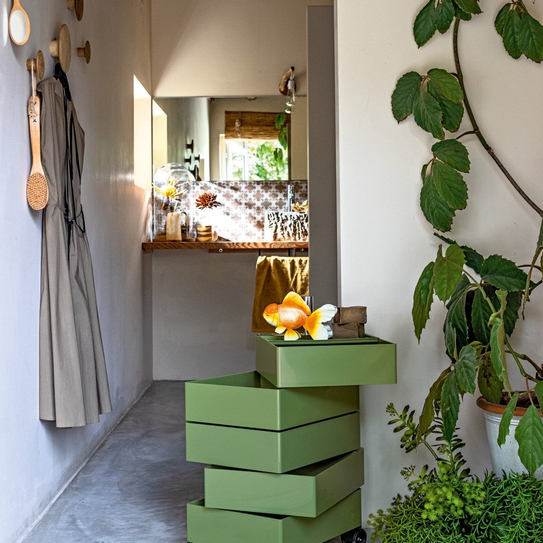 Green stackable storage boxes with glossy finish, accented by orange and yellow decorative elements in a modern interior.