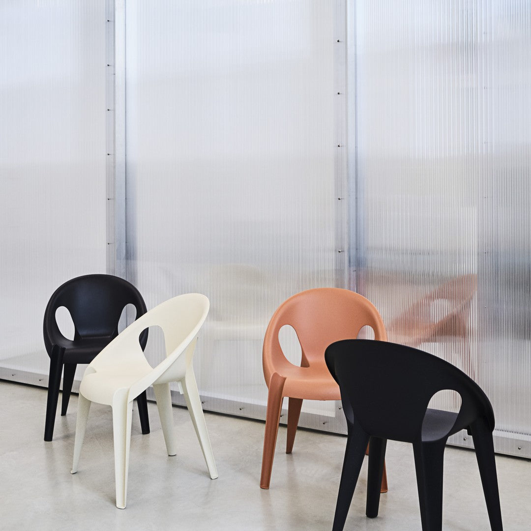 Colorful chairs in black, white, and orange, set against a neutral backdrop with modern patterns. Perfect for stylish decor.