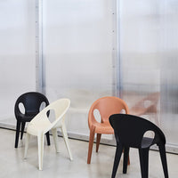 Colorful chairs in black, white, and orange, set against a neutral backdrop with modern patterns. Perfect for stylish decor.