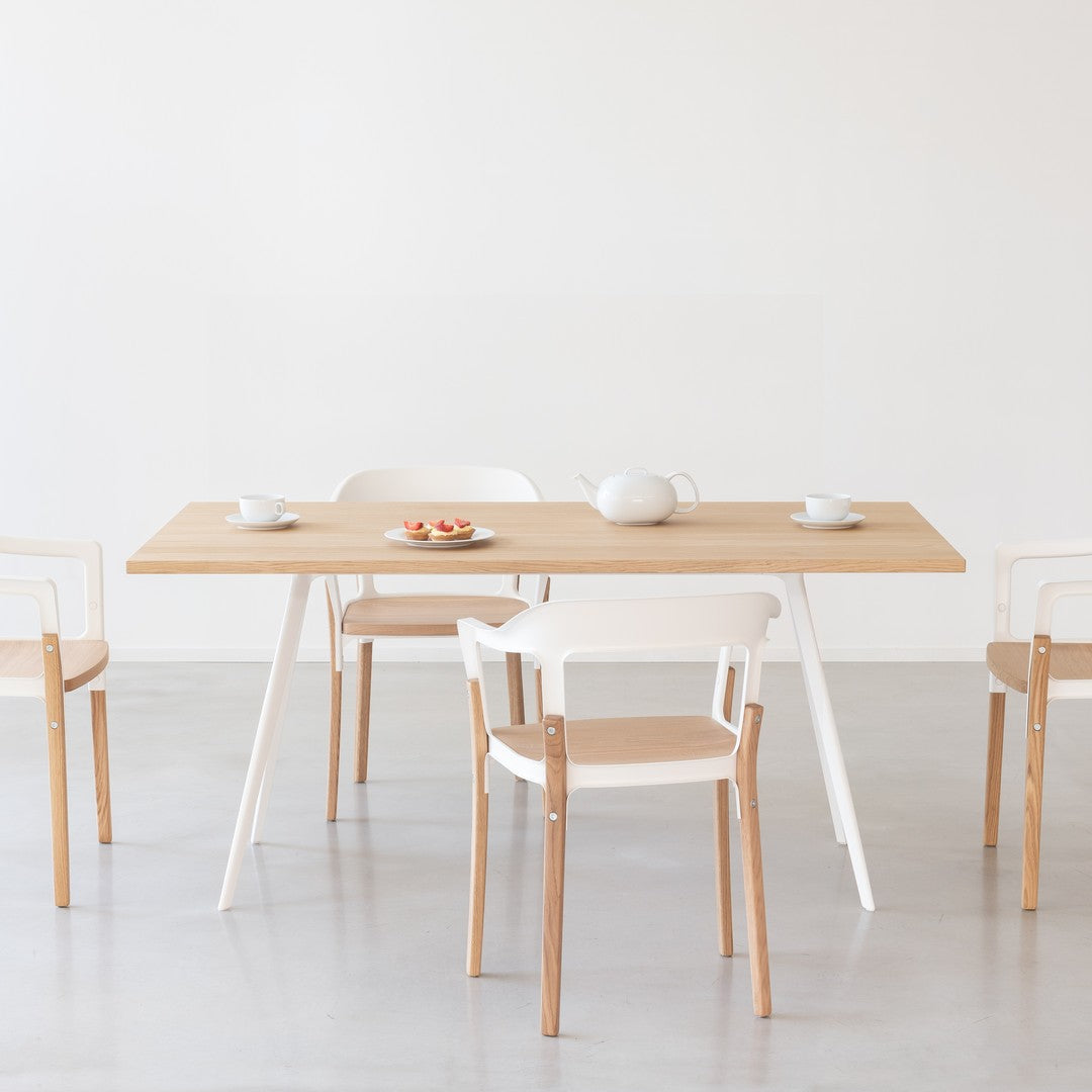 Light wood table with white chairs, featuring a minimalist design and soft color palette for a modern look.